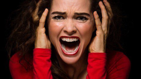 Close-up of a very angry, upset and desperate woman screaming